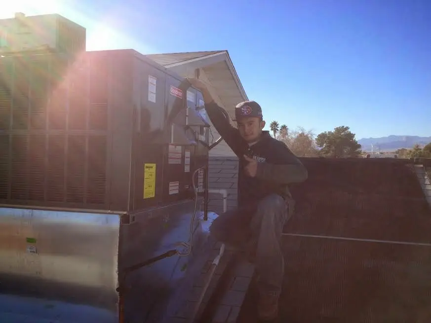 HVAC technician performing Air Duct Cleaning on a rooftop unit in Lawrenceville